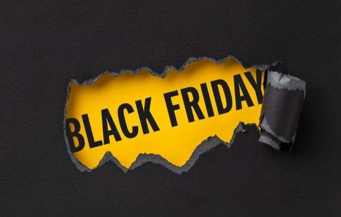 Testo del Black Friday su carta nera strappata che rivela un giallo brillante.