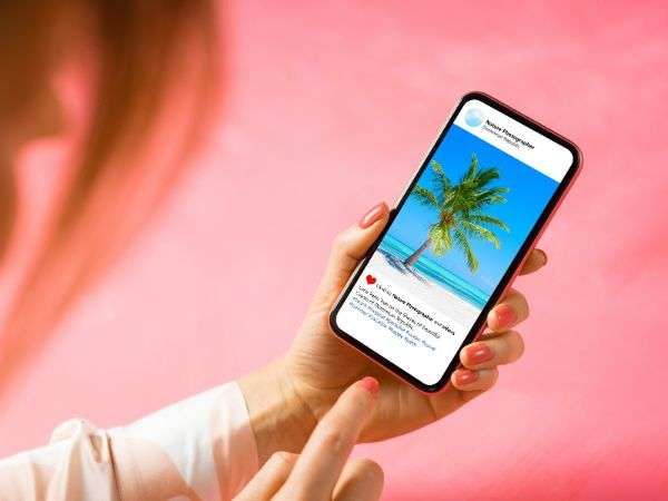Donna con in mano uno smartphone che scorre un post sui social media raffigurante una spiaggia con una palma.