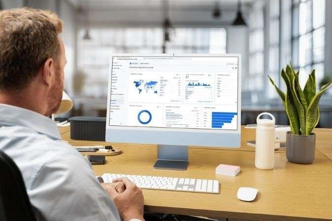 Uomo che visualizza il pannello di analisi su un computer azzurro in un ufficio.