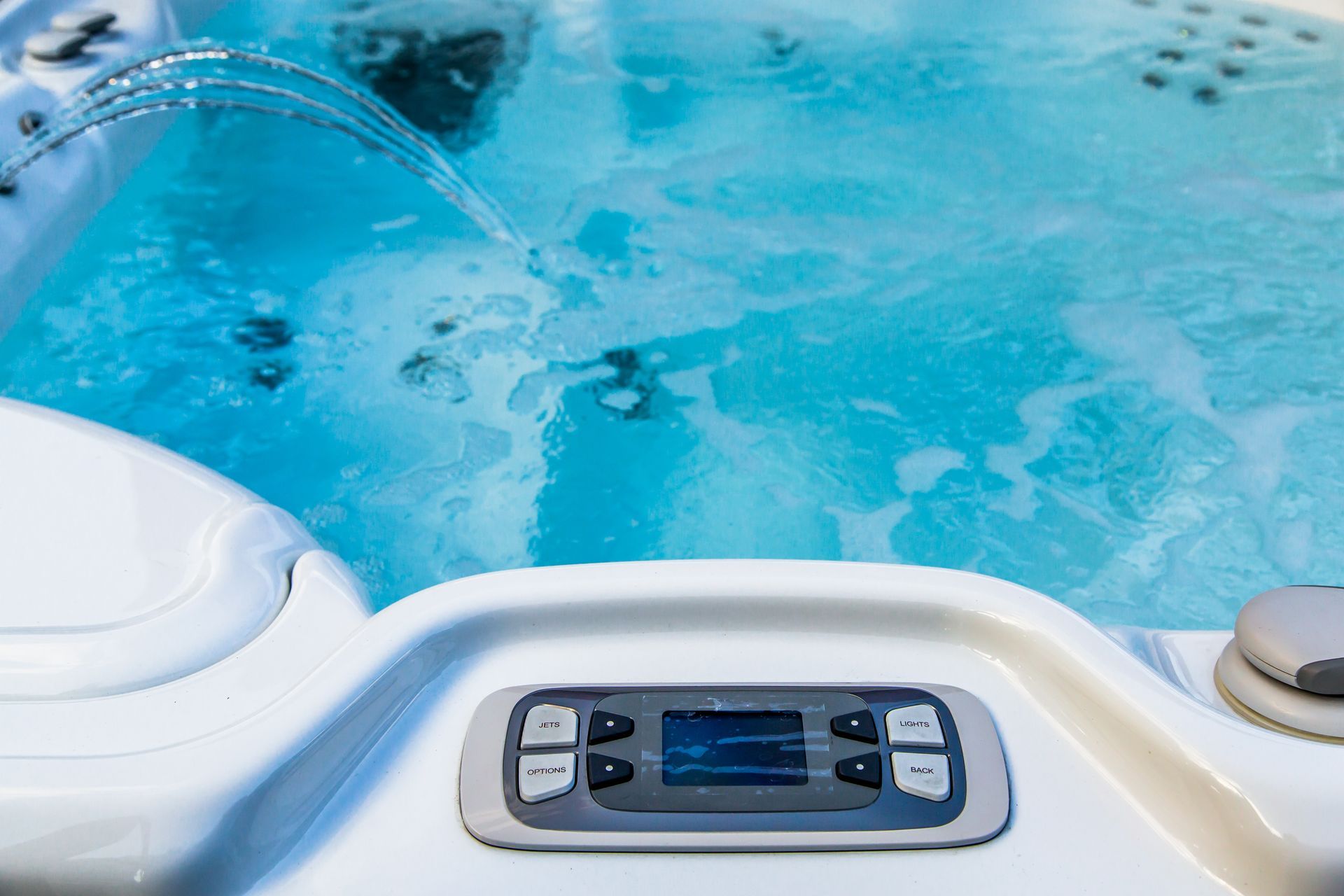 Hot tub control panel with blue bubbling water in the background