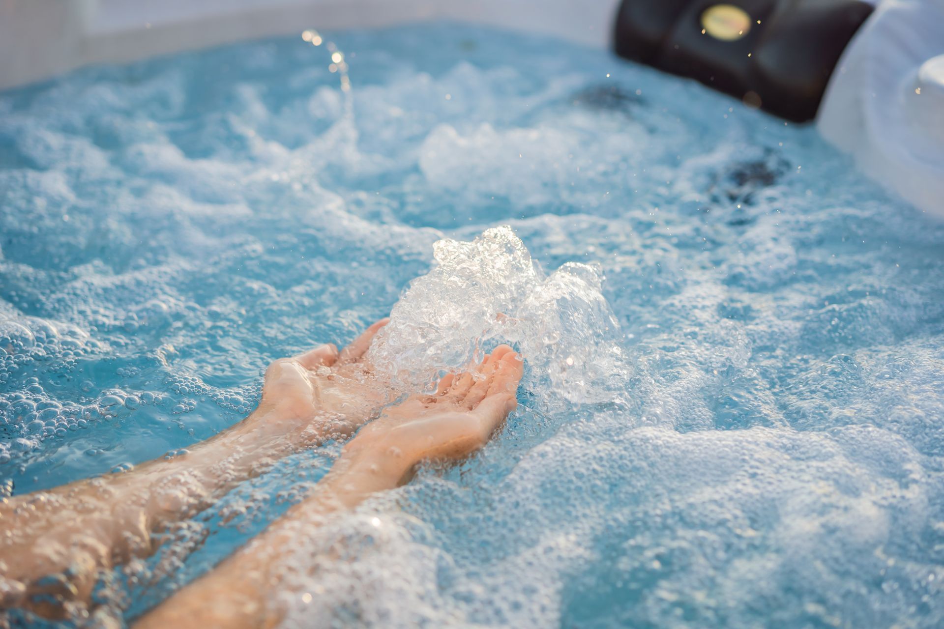 Hands in bubbling blue hot tub water with jets churning nearby