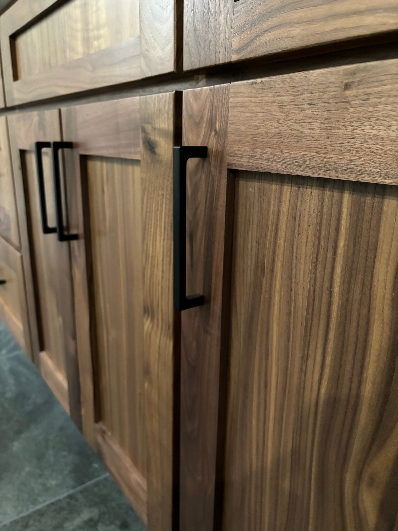A close up of a wooden cabinet with black handles.