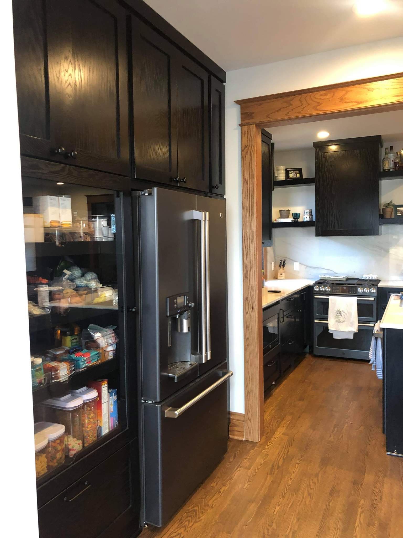 A kitchen with black cabinets and a black refrigerator.