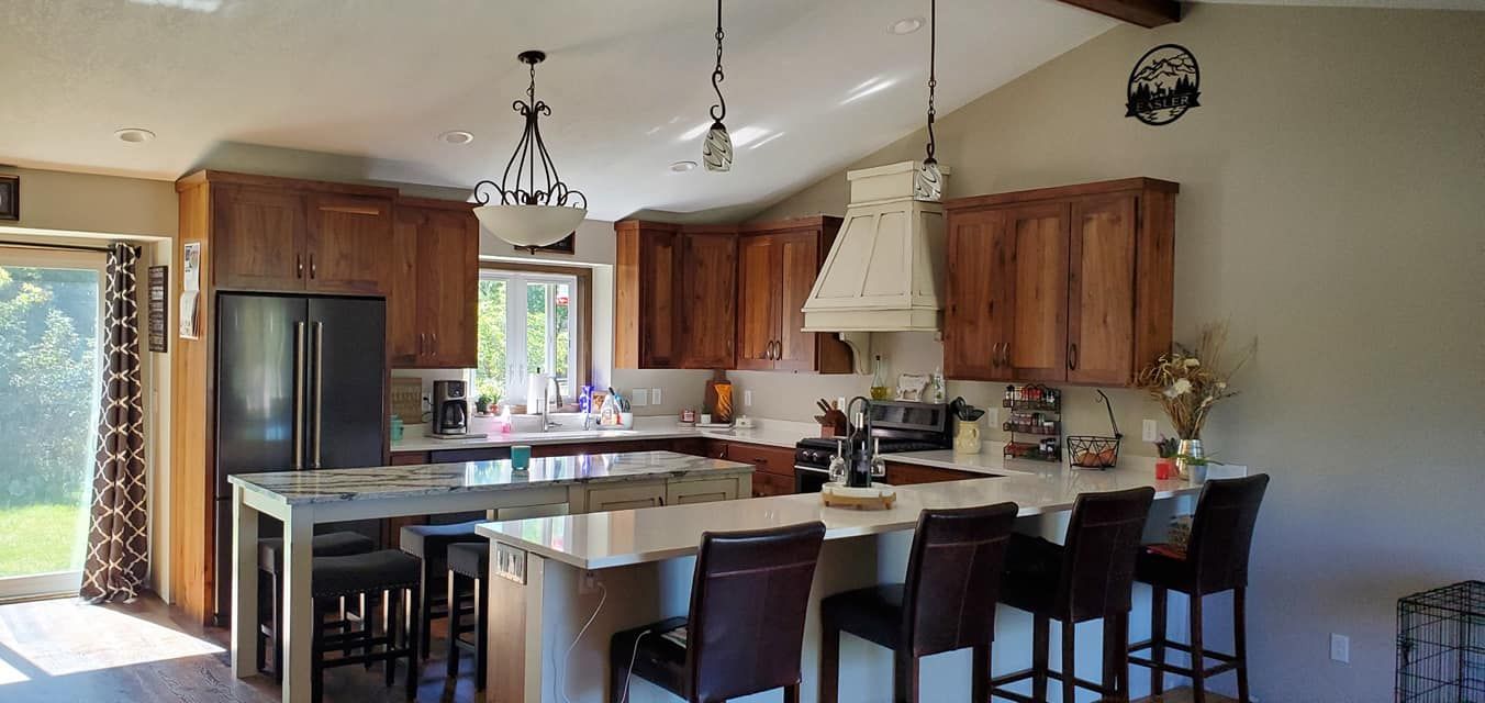 A kitchen with a large island , stools and a refrigerator.