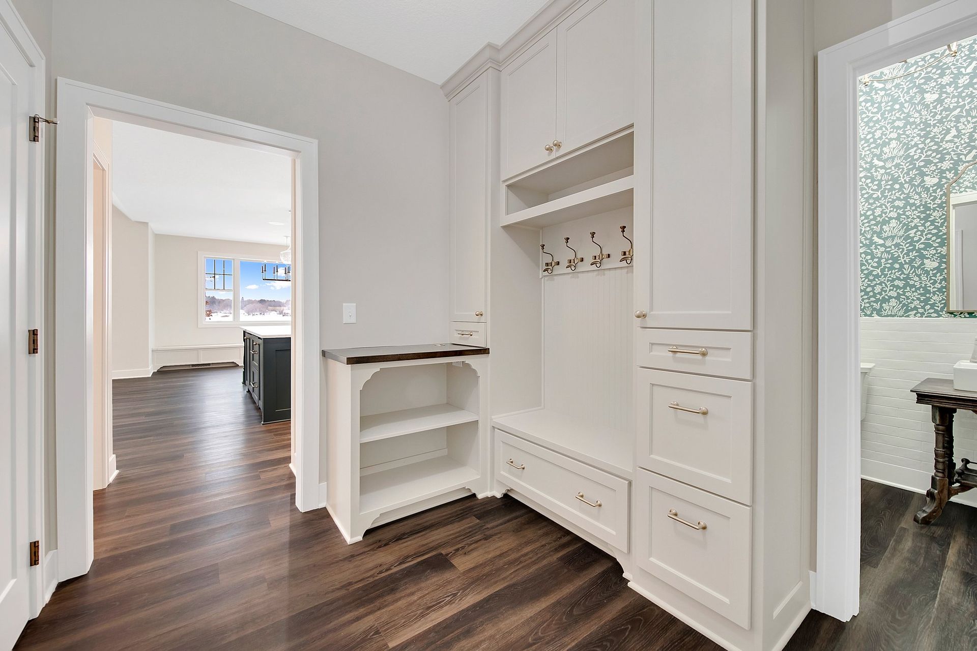 A hallway with hardwood floors and white cabinets in a house.