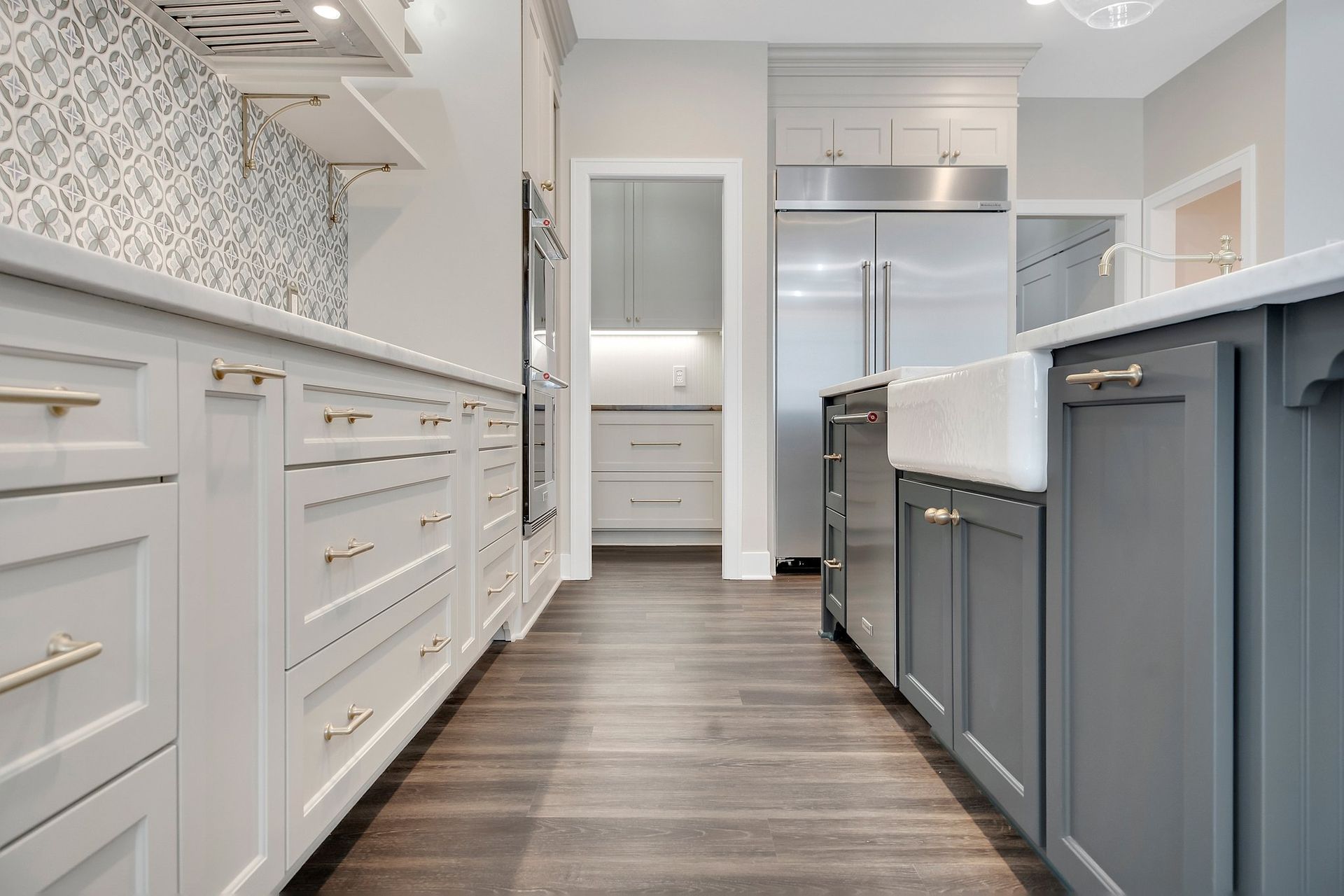 A kitchen with gray cabinets , white counter tops , stainless steel appliances and a sink.