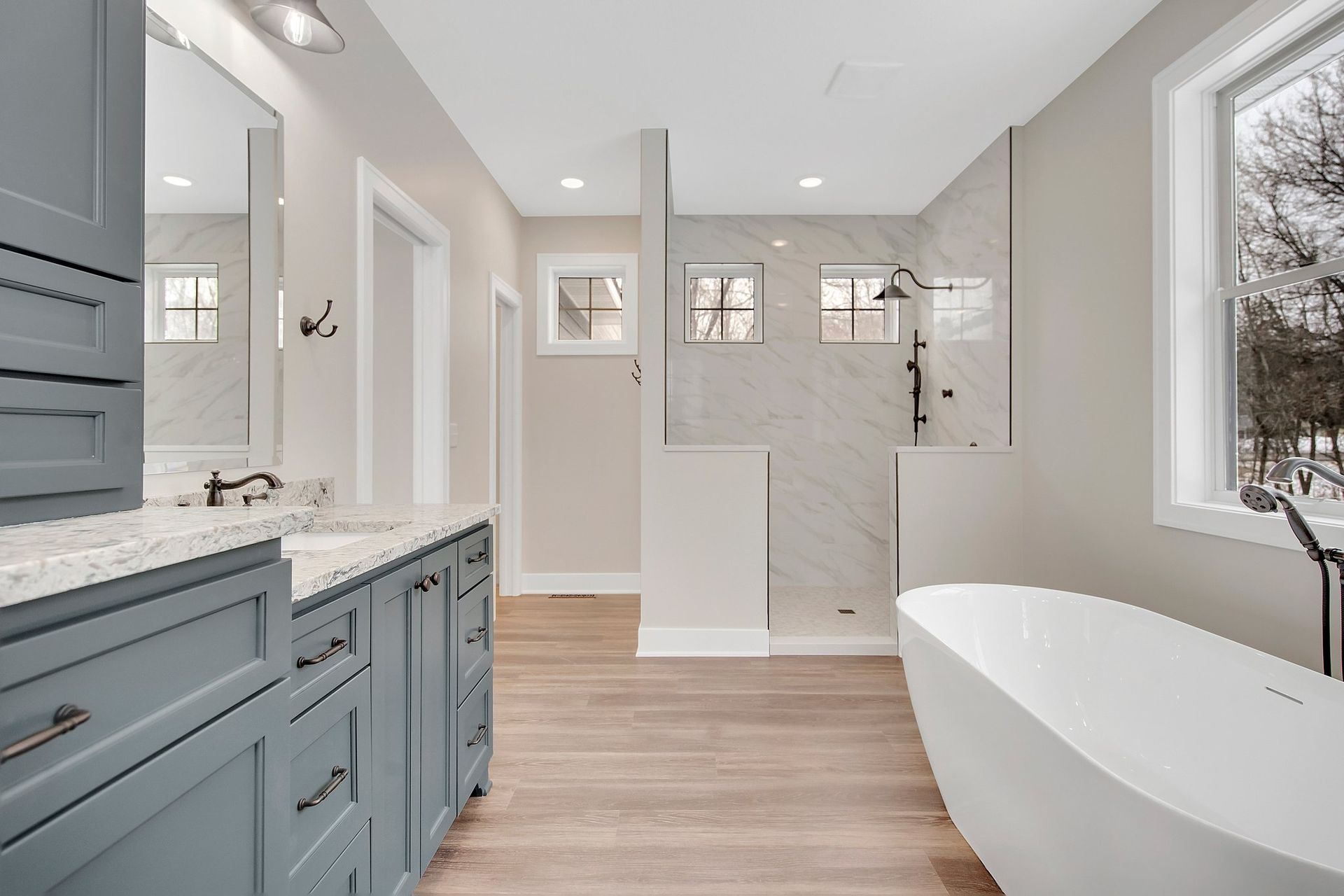 A bathroom with two sinks , a tub , a shower and a window.
