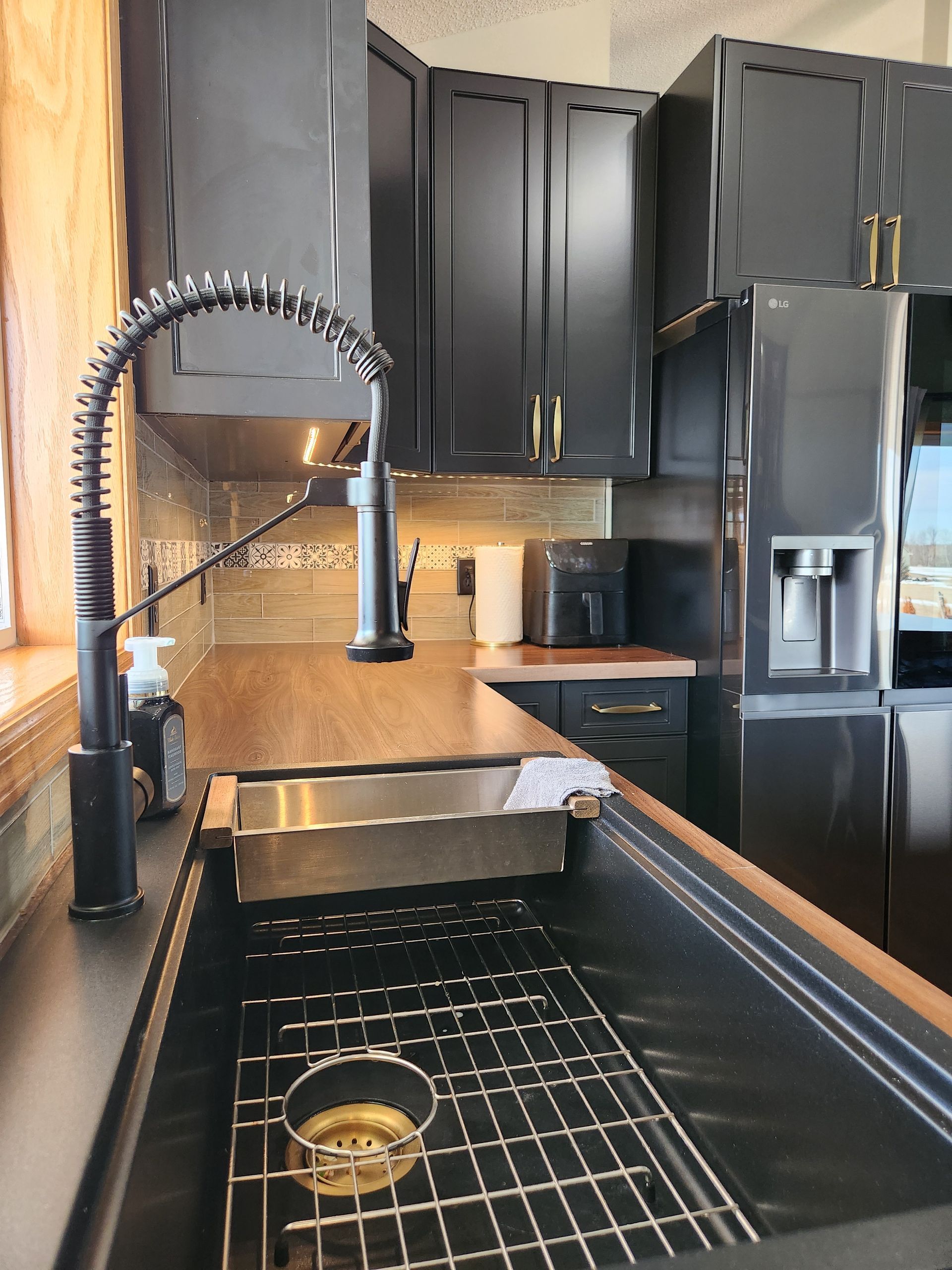A kitchen with black cabinets and a stainless steel sink