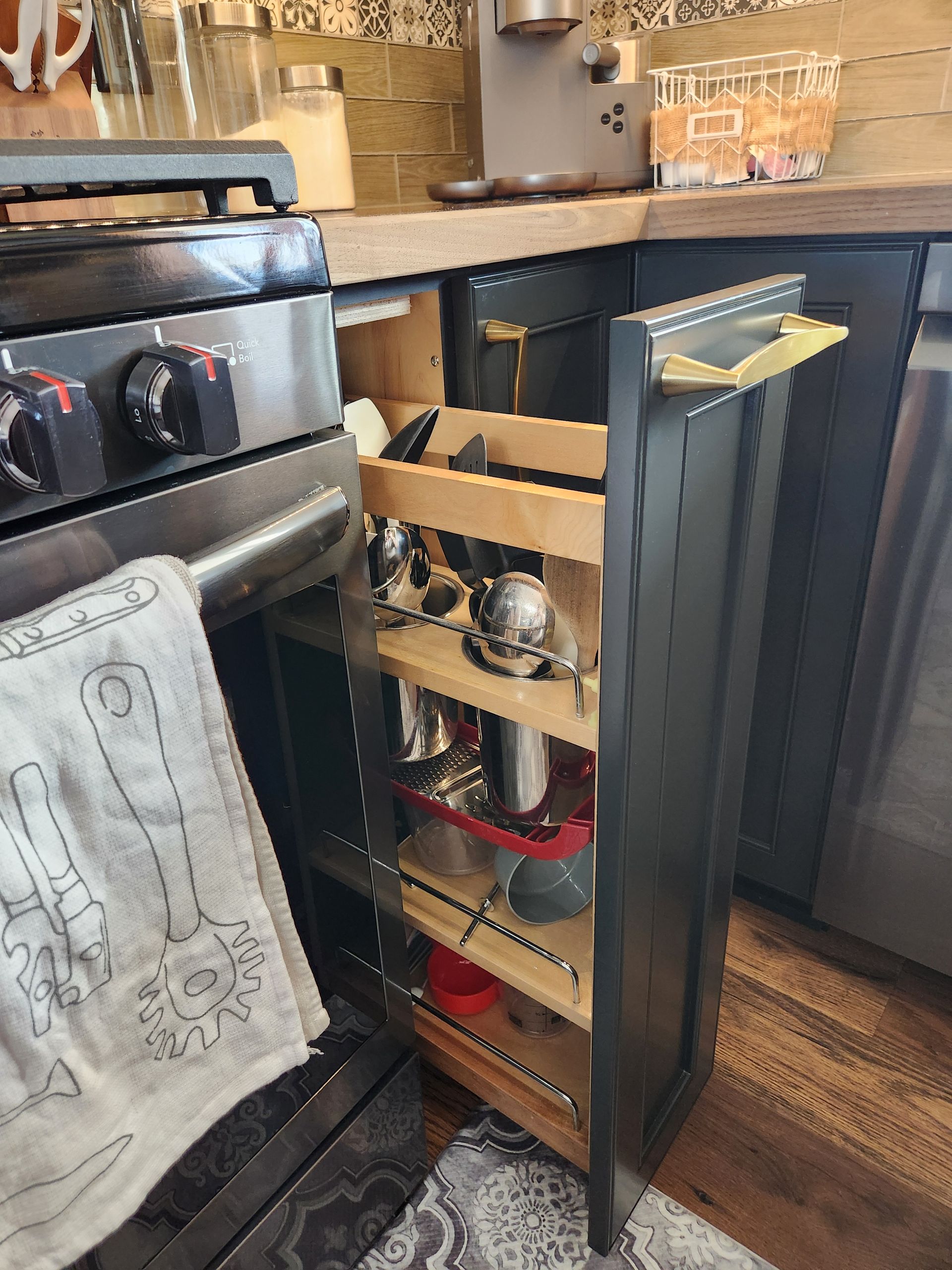 A kitchen with a stove and a drawer filled with pots and pans.