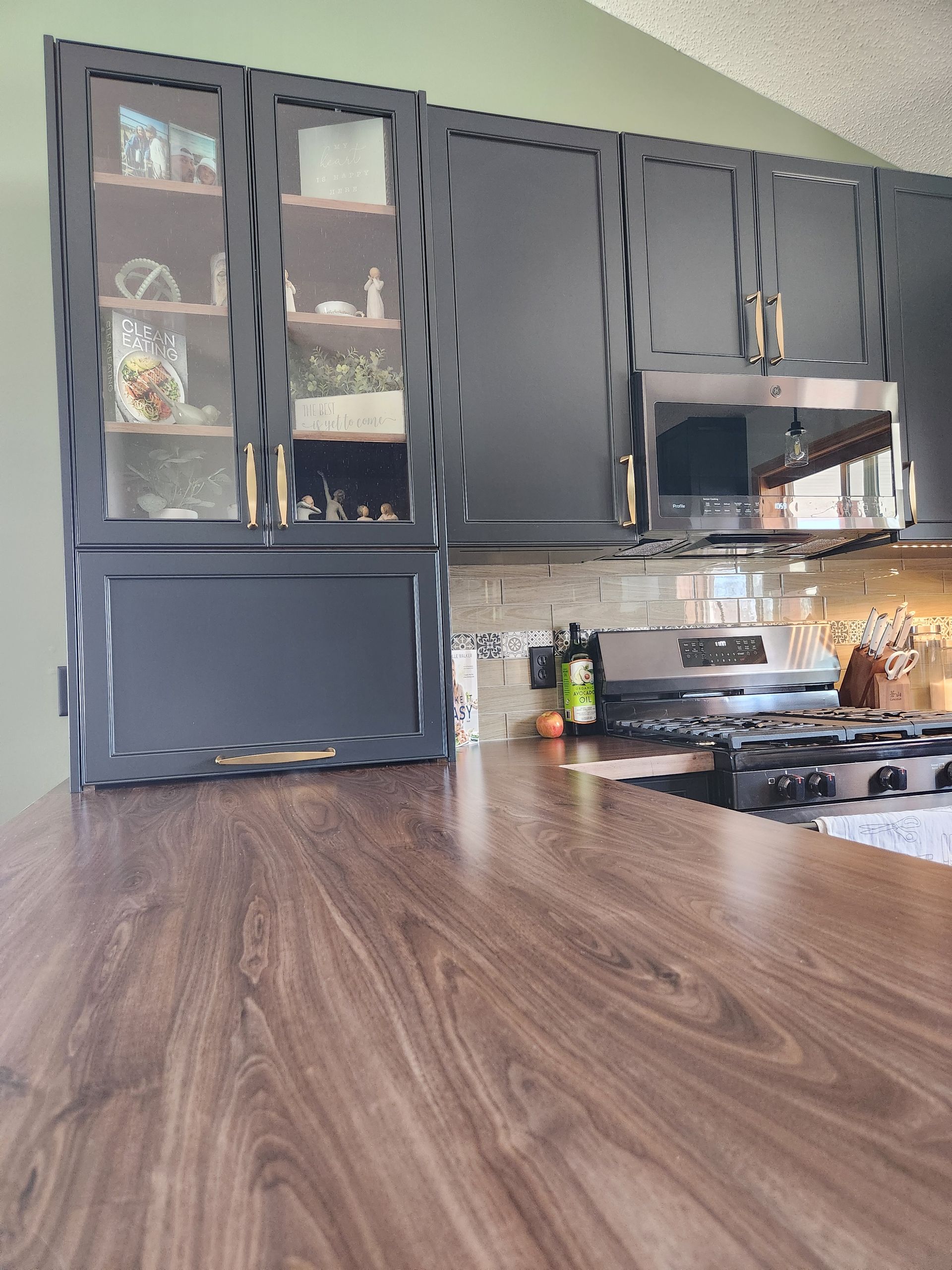 A kitchen with black cabinets and a wooden counter top.