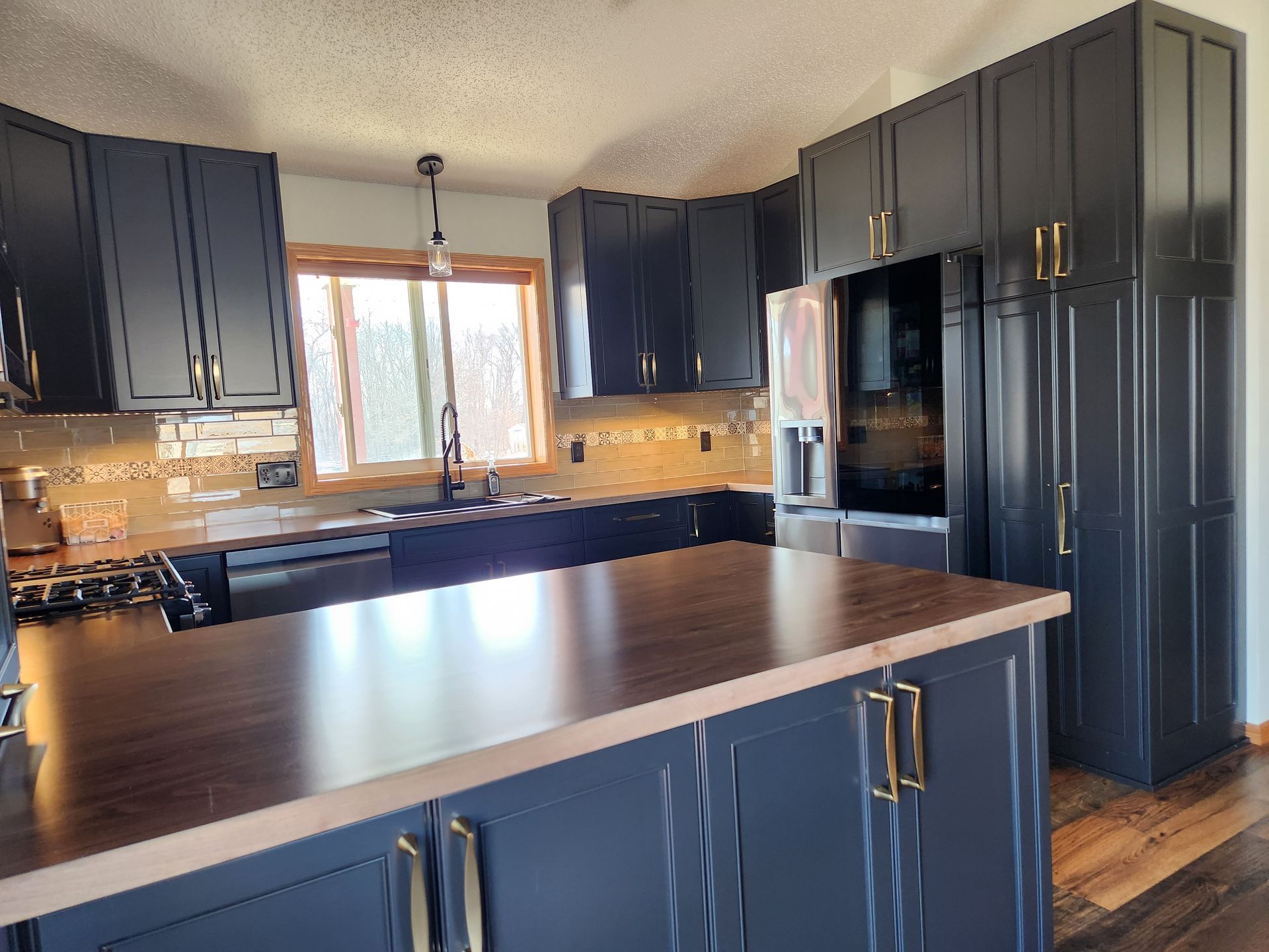 A kitchen with black cabinets and a wooden counter top.