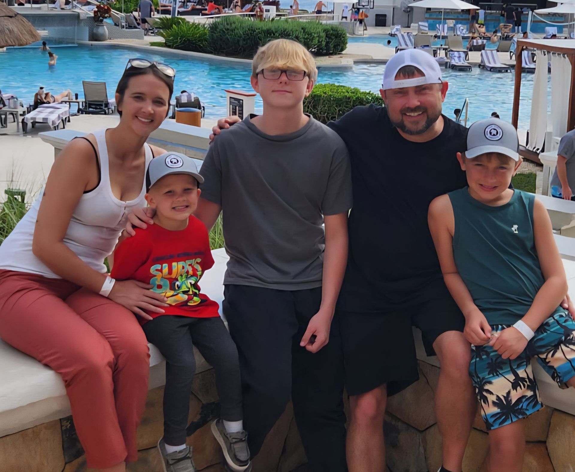 A family posing for a picture in front of a swimming pool A family posing for a picture in front of a swimming pool