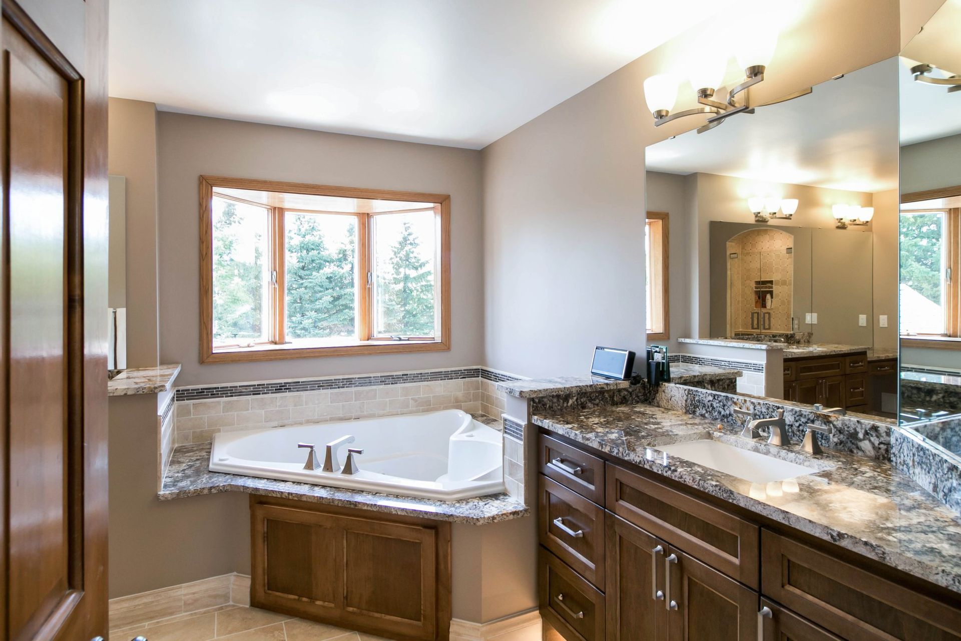A bathroom with a tub , sinks , and a large mirror.