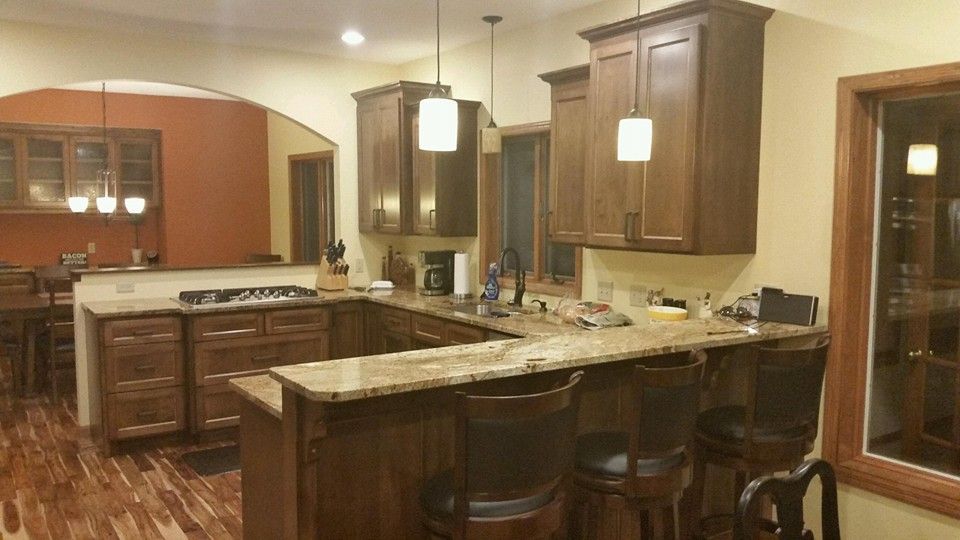 A kitchen with wooden cabinets , granite counter tops , and stools.
