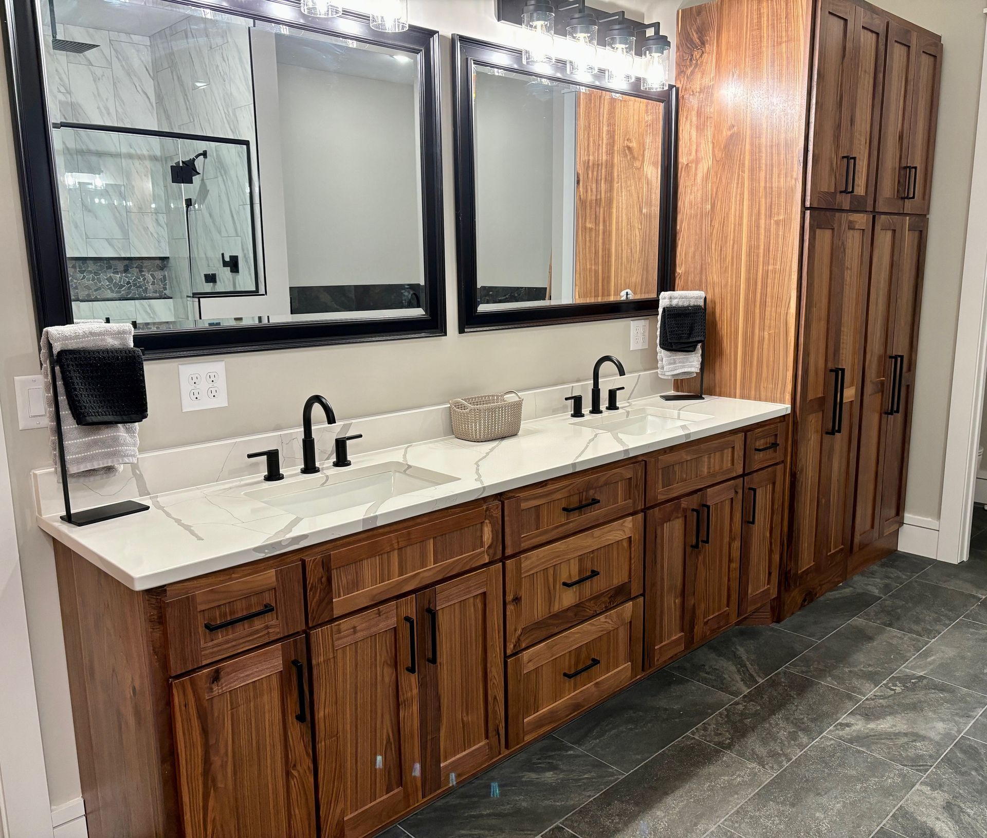 A bathroom with two sinks , two mirrors , and wooden cabinets.