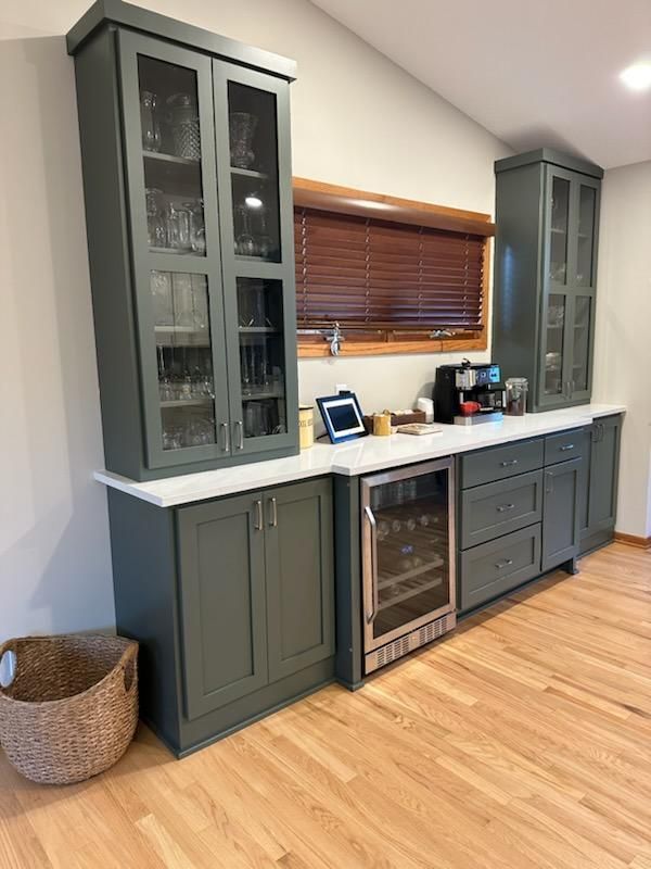 A kitchen with gray cabinets and a wine cooler.