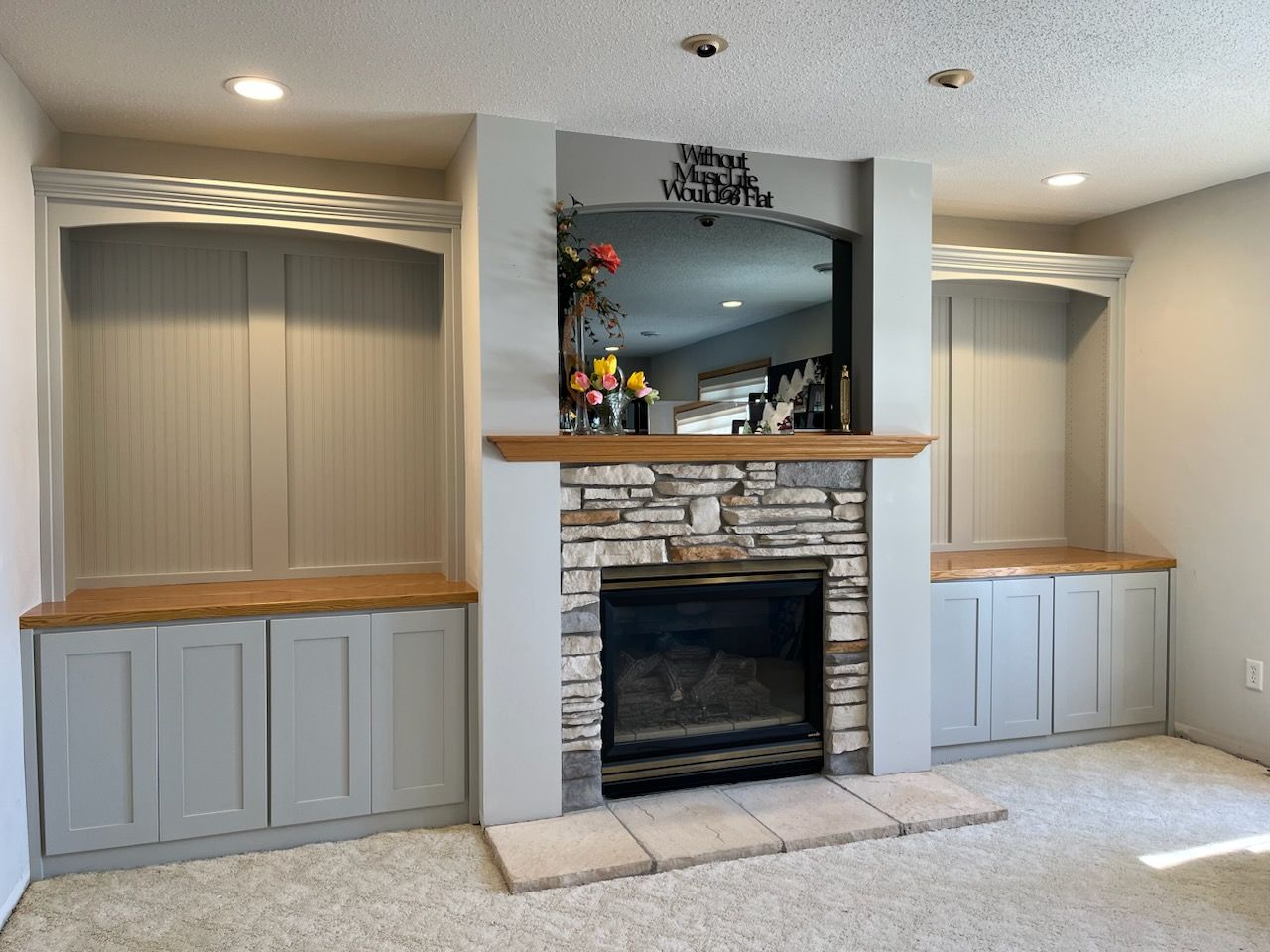 A living room with a fireplace and built in cabinets