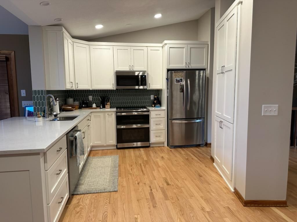 A kitchen with white cabinets , stainless steel appliances , and hardwood floors.