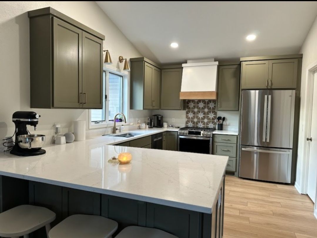 A kitchen with stainless steel appliances and green cabinets