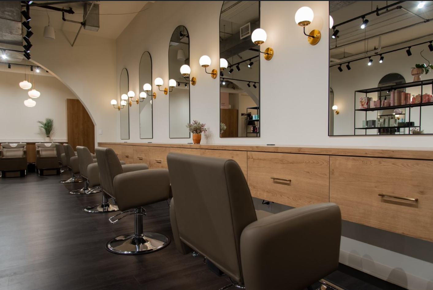 A row of chairs in a hair salon with mirrors.