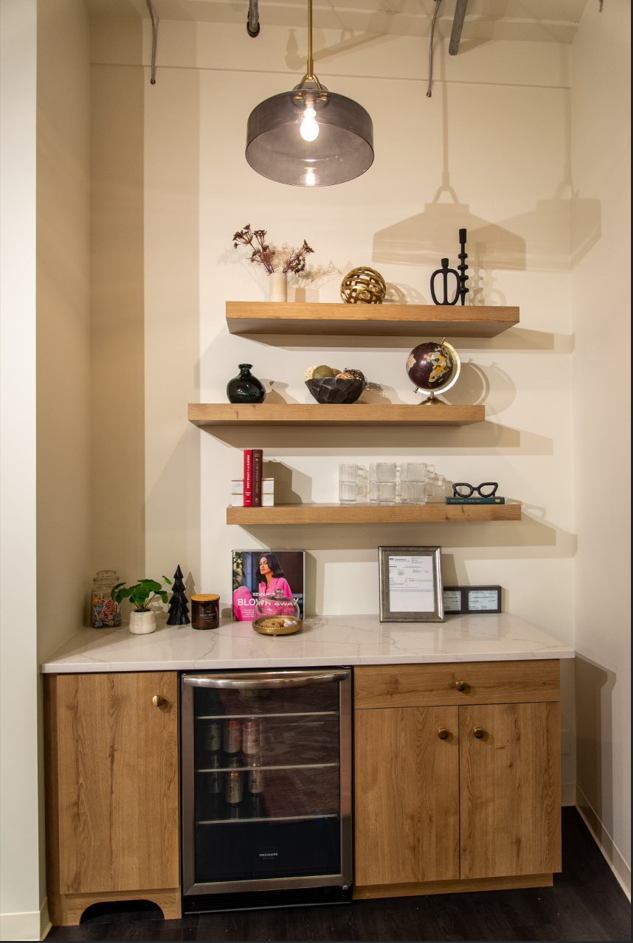 A kitchen with wooden cabinets , a refrigerator and shelves.