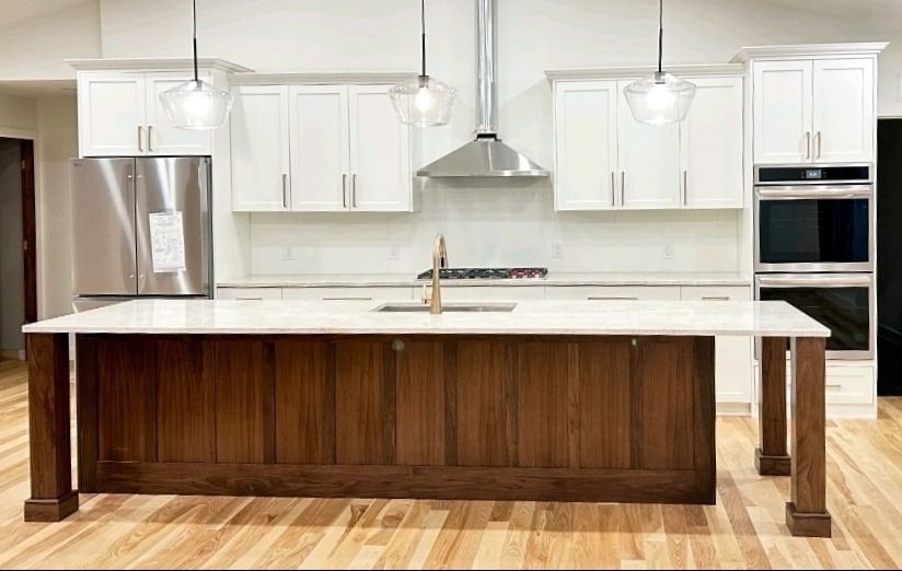 A kitchen with white cabinets , stainless steel appliances , and a large island.