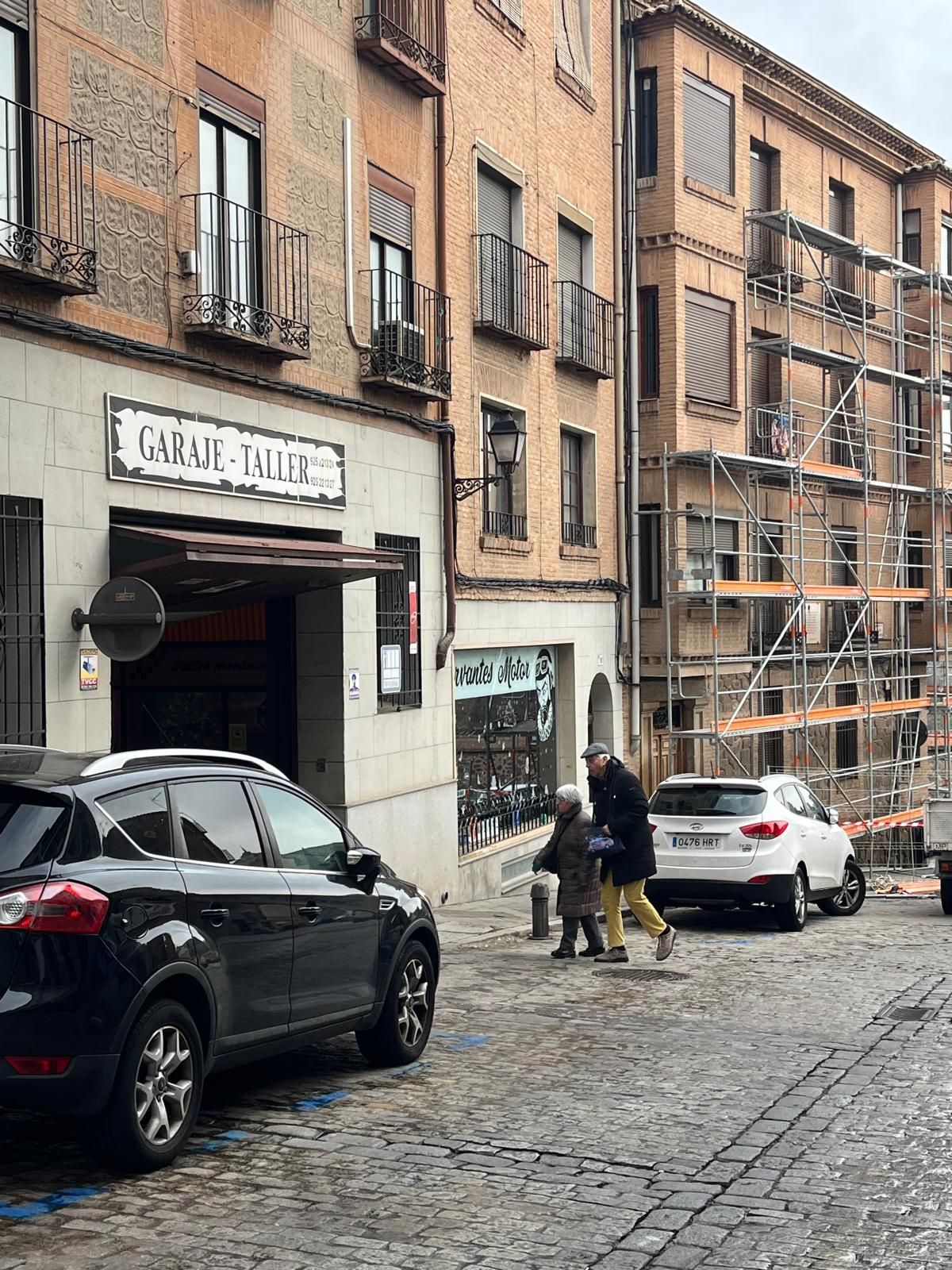 Un SUV negro estaba estacionado en una calle empedrada cerca de la entrada de un edificio con la inscripción