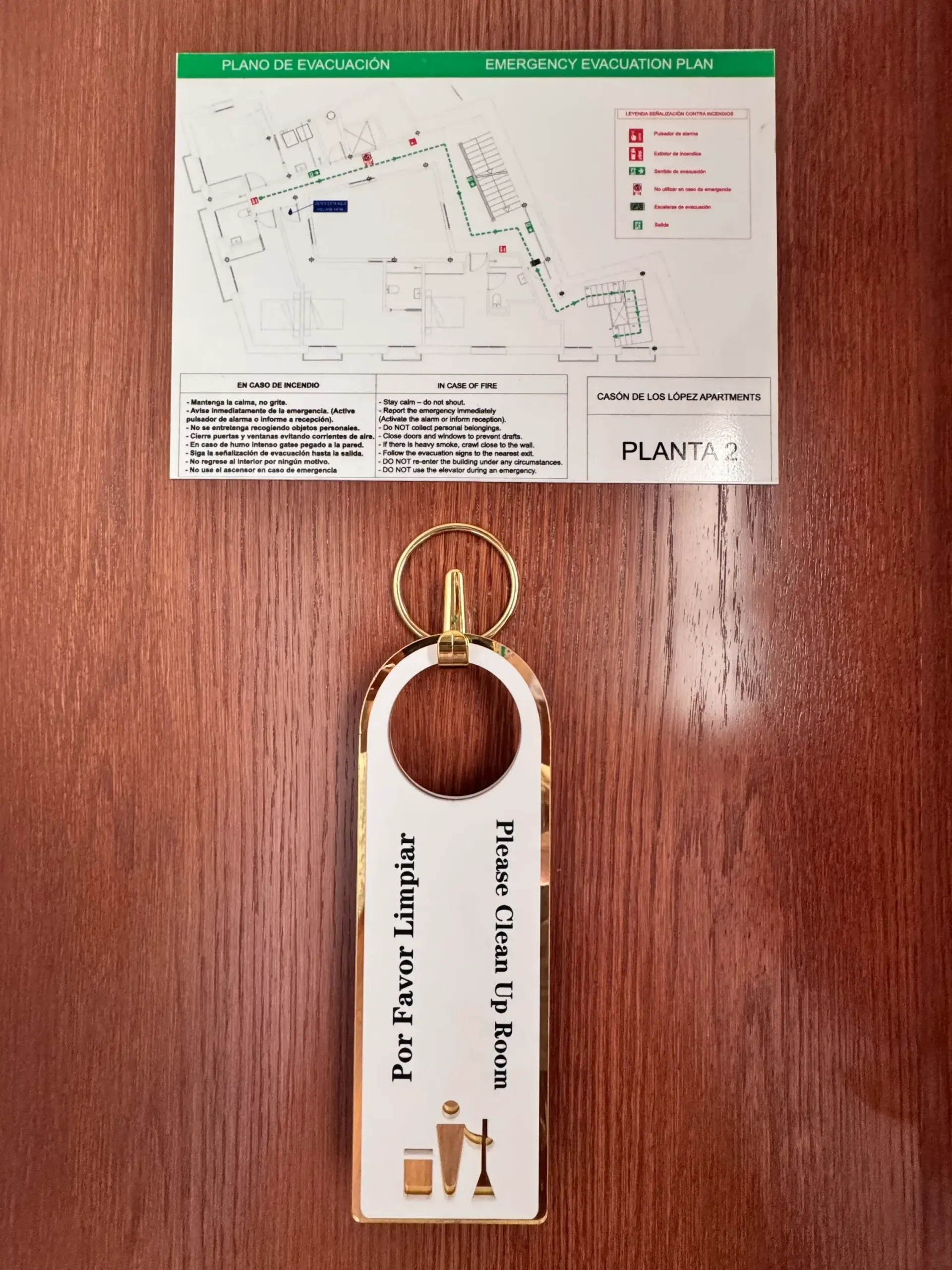 Un cartel en la puerta de una habitación de hotel colgado de un gancho, con un plano de la planta en la parte superior y una etiqueta con el texto 