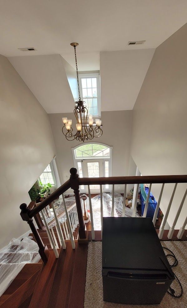 A staircase leading up to a living room with a chandelier hanging from the ceiling.