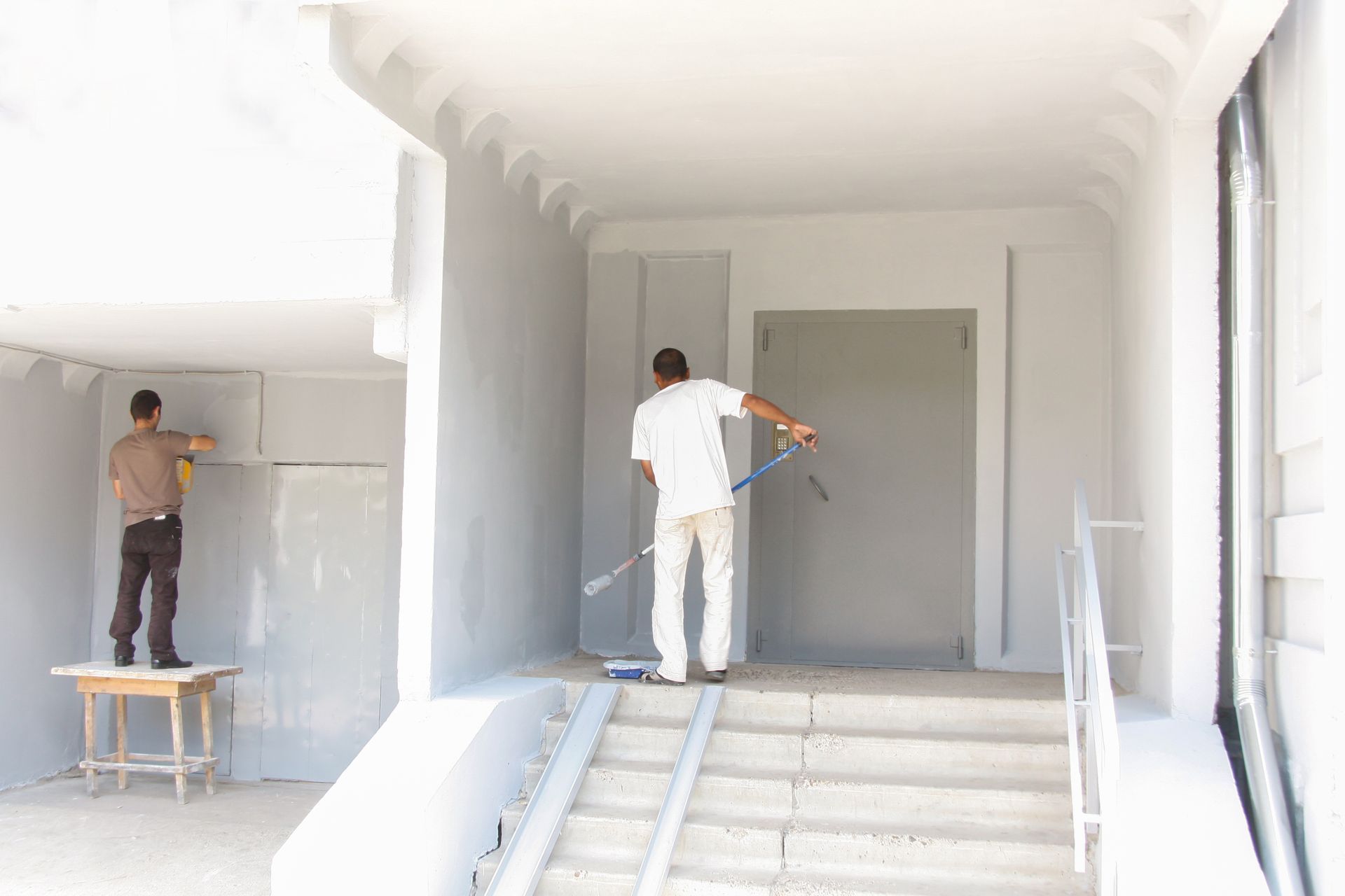 Two Painters Applying Plaster To Walls Inside A Building — TMP Painting Services in Paget, QLD