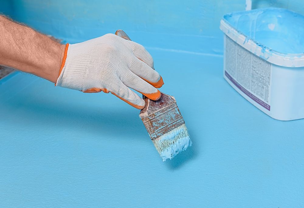 Person Painting A Blue Surface With A Brush, Wearing Gloves — TMP Painting Services in Beaconsfield, QLD