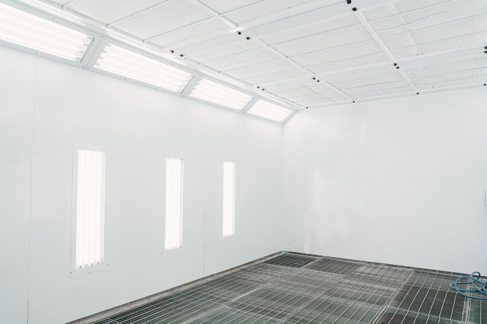 Empty, white spray paint booth with ceiling lights and floor grating — TMP Painting Services in Beaconsfield, QLD