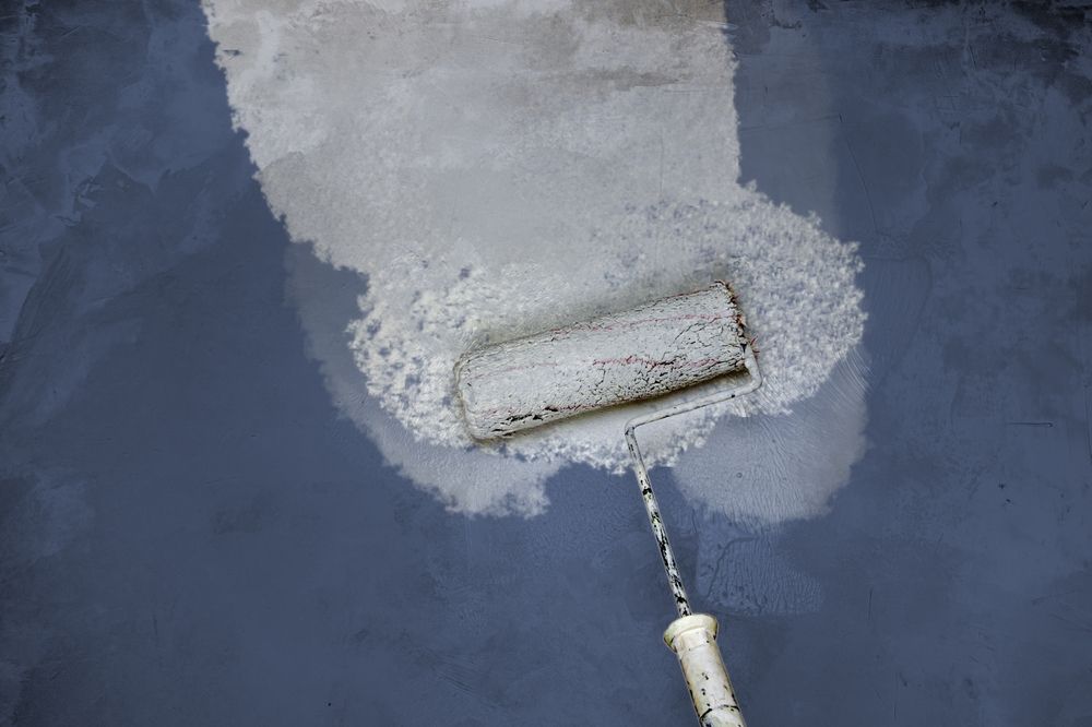 A paint roller applying white paint to a dark blue surface — TMP Painting Services in Beaconsfield, QLD