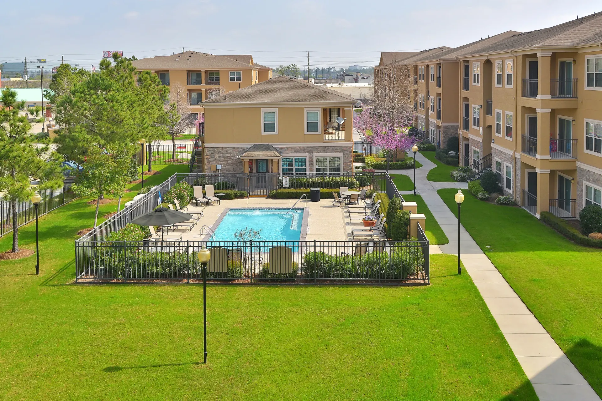 Outdoor pool area with lounge chairs surrounded by apartment buildings.