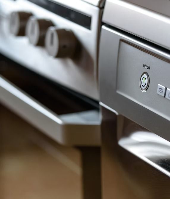Stainless steel oven and dishwasher with knobs and control buttons.