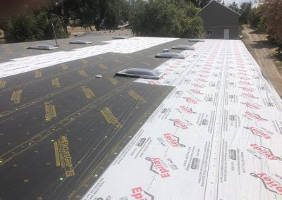 A roof with a lot of shingles on it and a house in the background.