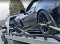 A black sports car is being towed by a tow truck.