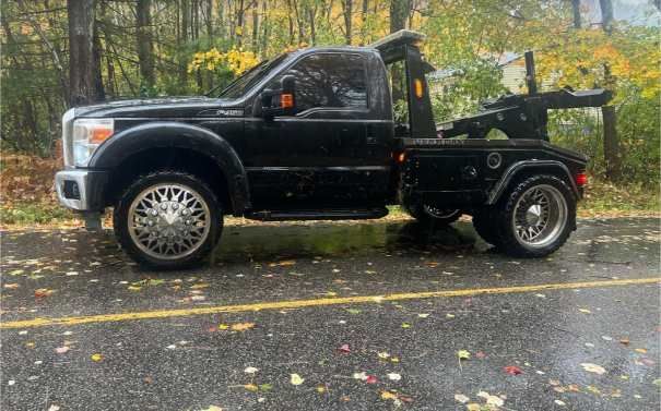A black tow truck is parked on the side of the road.