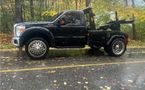 A black tow truck is parked on the side of the road.