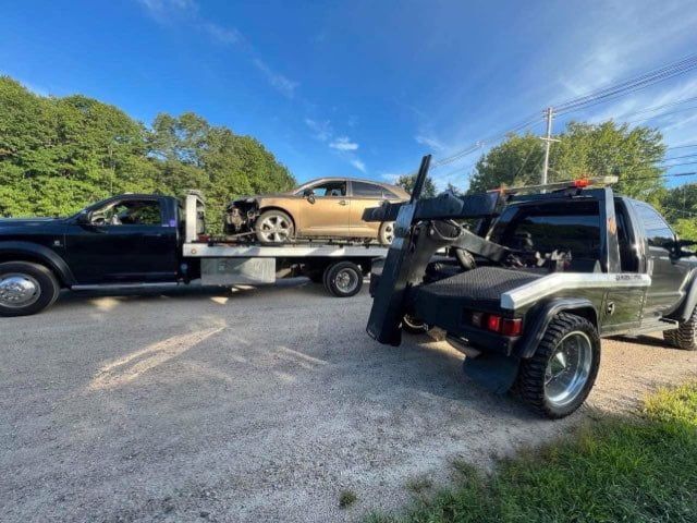 A tow truck is carrying a car on the back of it.