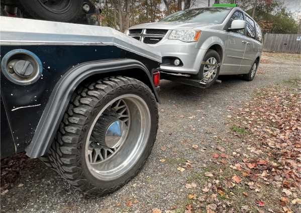 A silver car is being towed by a tow truck.