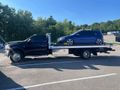 A blue car is being towed by a tow truck in a parking lot.