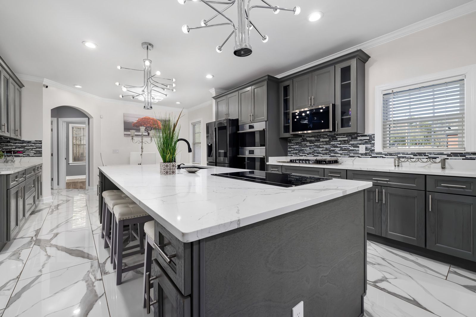 A kitchen with gray cabinets , white counter tops , and a large island.