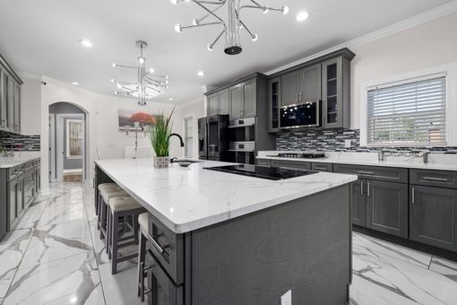 A kitchen with gray cabinets , white counter tops , and a large island.