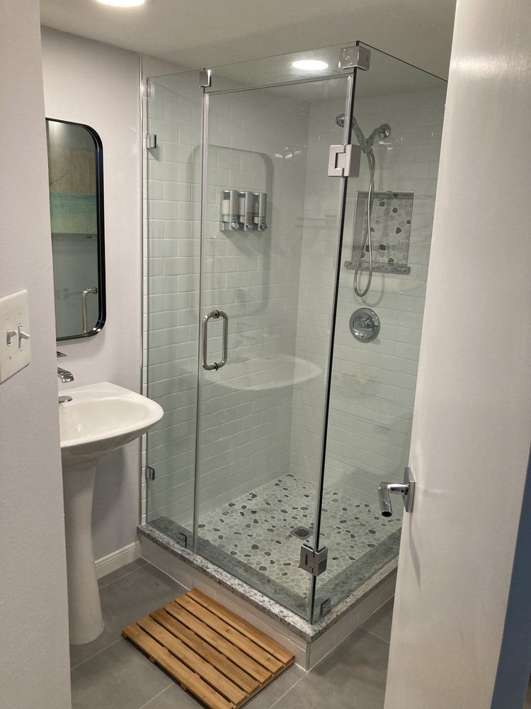 A bathroom with a walk in shower , sink and mirror.