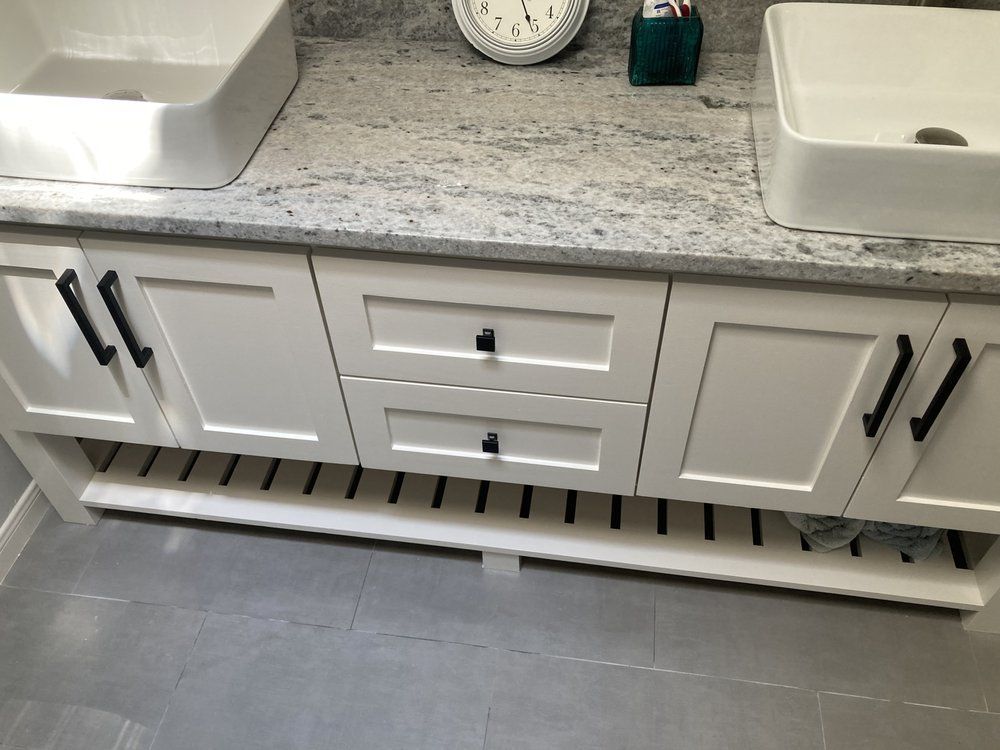A bathroom vanity with two sinks and a clock on the counter.