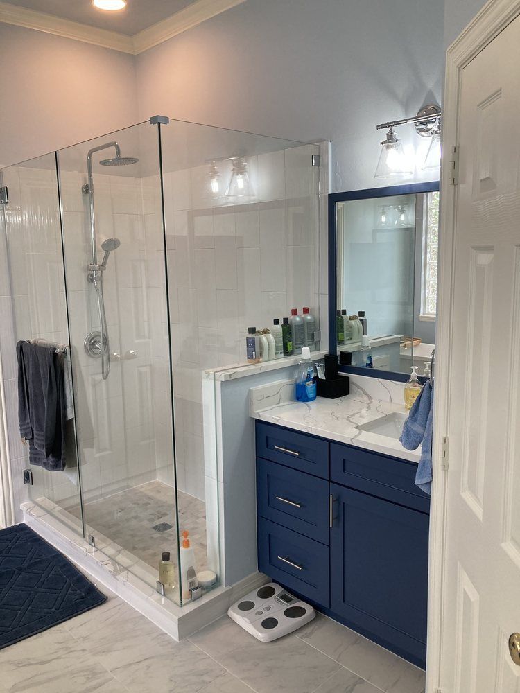 A bathroom with a walk in shower , sink , mirror and scale.