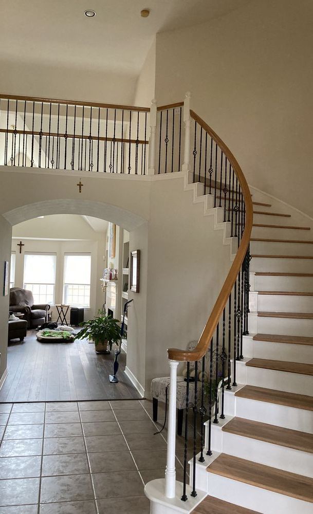 A man in a blue shirt is standing in front of a staircase in a house.