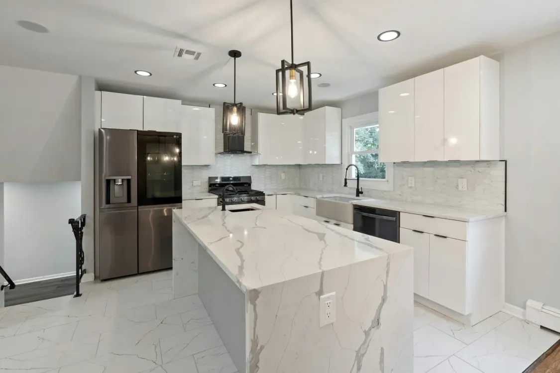 A kitchen with white cabinets , stainless steel appliances , and a large island.