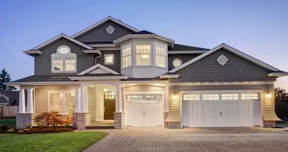 A large house with a lot of windows and a garage is lit up at night.